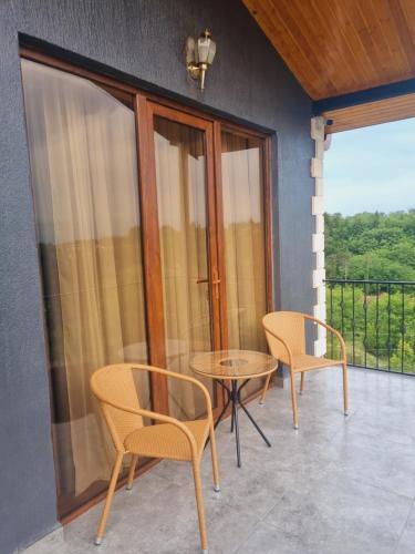 a patio with two chairs and a table and a balcony at Lake House in Tskaltubo