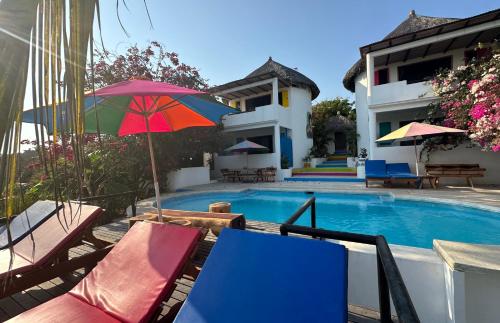 a pool with chairs and umbrellas next to a house at Beachfront Paradise Boutique Hotel - Breeze Room ll in Playa Agua Blanca