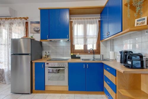 a kitchen with blue cabinets and a stainless steel refrigerator at BS Village in Metamorfosi