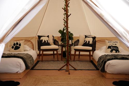 a room with three beds and two chairs in a tent at Grotto Getaway in Miller Lake
