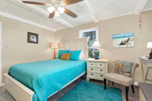 a bedroom with a blue bed and a chair at Suncatcher Cottage 1508-2nd Avenue B in Tybee Island