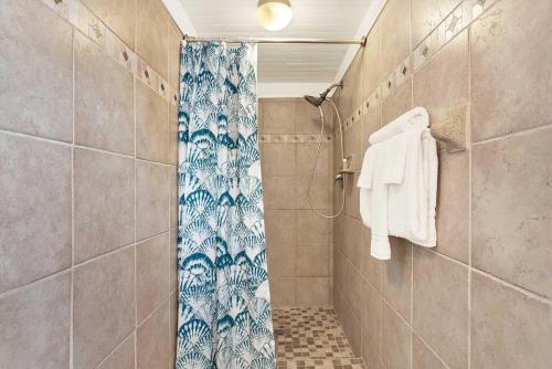 a shower with a blue shower curtain in a bathroom at Suncatcher Cottage 1508-2nd Avenue B in Tybee Island