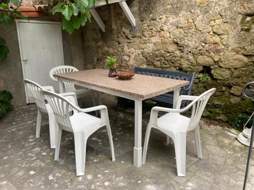 une table, quatre chaises, une table et un mur dans l'établissement Maison RASSIER, Gîte Vélo, à Sainte-Eulalie