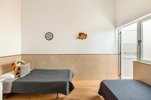 two beds in a room with a clock on the wall at SALINETAS BLUE SURF HOUSE in Telde
