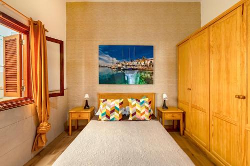 a bedroom with a bed with two tables and a painting on the wall at SALINETAS BLUE SURF HOUSE in Telde