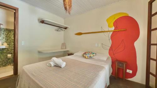 a room with two beds and a painting of a bird on the wall at Mangará Hostel e Hospedaria in Ilhabela
