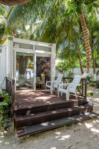 a porch with white chairs and palm trees at Hotel Reina del Mar By Dorado in San Andrés
