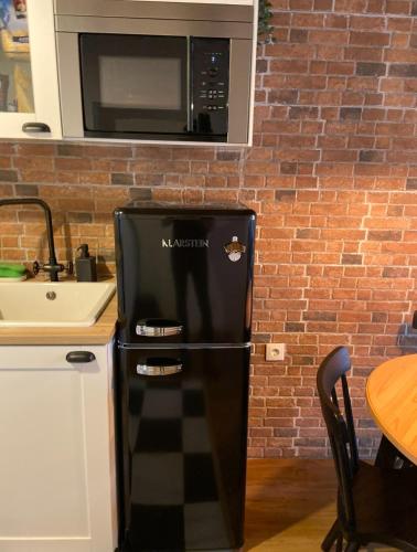 a black refrigerator in a kitchen with a microwave at AL Belém 85 in Lisbon