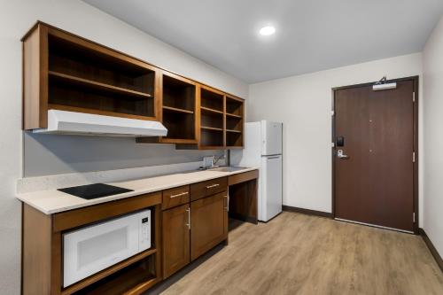 a kitchen with wooden cabinets and a white refrigerator at WoodSpring Suites Palmdale - Lancaster in Palmdale