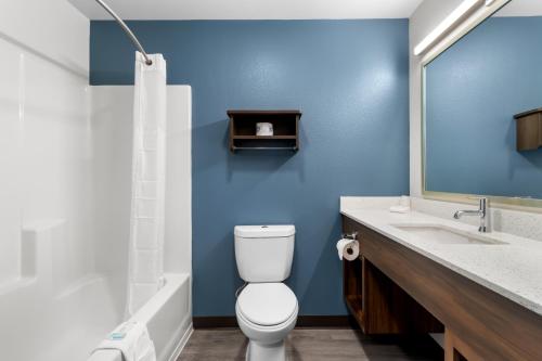 a bathroom with a white toilet and a blue wall at WoodSpring Suites Palmdale - Lancaster in Palmdale