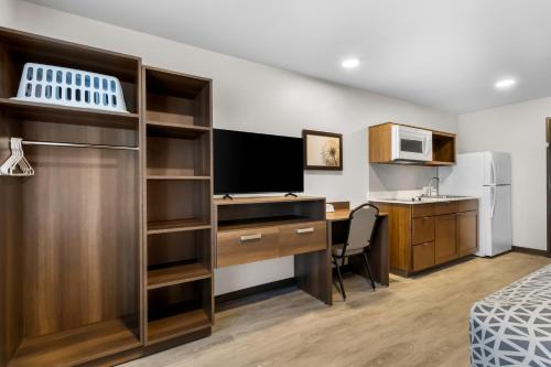 a hotel room with a desk and a computer and a kitchen at WoodSpring Suites Palmdale - Lancaster in Palmdale
