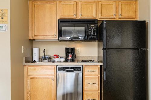 a kitchen with wooden cabinets and a black refrigerator at Valleyview Swing & Stay in Traverse City