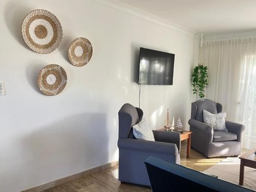 a living room with two chairs and a tv on the wall at Apartamento en Punta Cana, White sands in Punta Cana