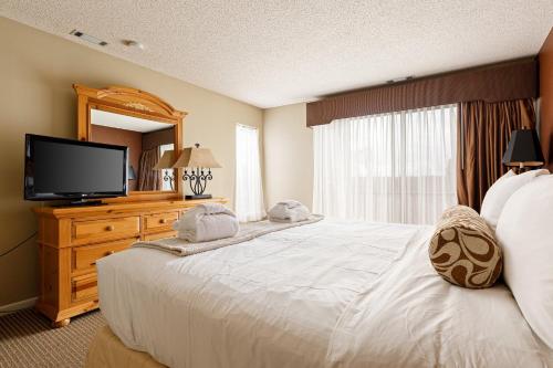a bedroom with a large white bed with a flat screen tv at Valleyview Swing & Stay in Traverse City