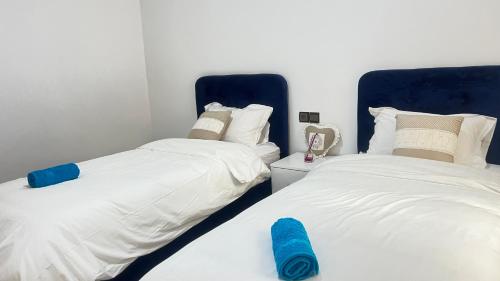 two beds sitting next to each other in a bedroom at Magnifique maison famiiale moderne spacieuse de 150 m Avec de 3 chambres ,confortables et d un grand salon et terrasse, Idealement situee a 9 min du centre-ville elle se trouve à proximite de la route principale menant a l aeroport Berkane et Saidia in Oujda