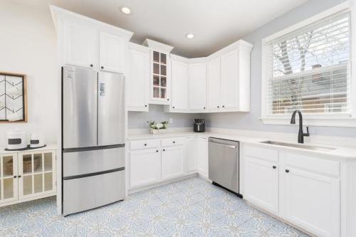 a kitchen with white cabinets and a stainless steel refrigerator at Stunning 2 Bedroom Apt in Historic Springfield in Jacksonville