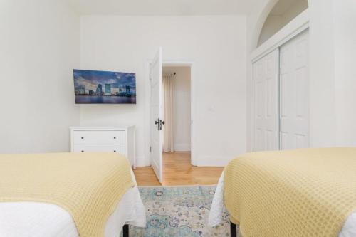 a white bedroom with two beds and a painting on the wall at Stunning 2 Bedroom Apt in Historic Springfield in Jacksonville
