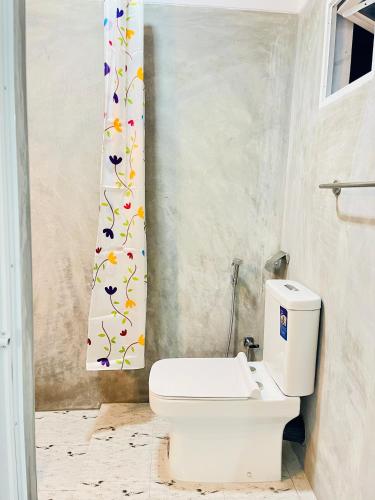 a bathroom with a toilet and a shower curtain with flowers at Dreamy Heaven Negombo in Negombo