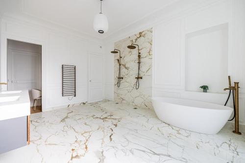 une salle de bain avec une baignoire blanche et un sol en marbre dans l'établissement Luxurious 4 Bedroom Apartment, La Muette, à Paris