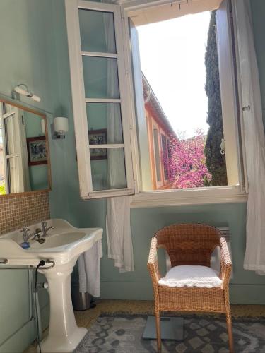 La salle de bains est pourvue d'un lavabo, d'une fenêtre et d'une chaise. dans l'établissement maison 3 chambres centre ville, jardin et bassin privatifs, à Montpellier