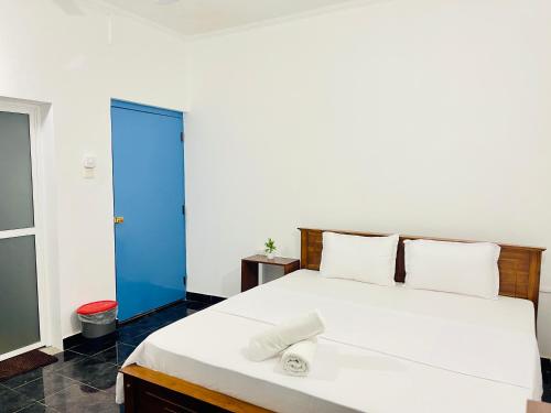 a bedroom with a white bed with a blue door at Dreamy Heaven Negombo in Negombo