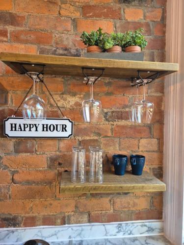 a shelf with glass jars and a happy hour sign on a brick wall at City Centre Sanctuary with parking space in Worcester