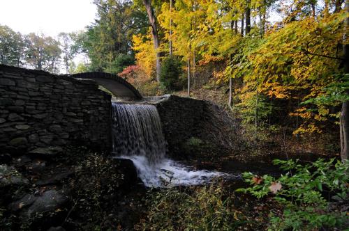 a stone bridge over a stream with a waterfall at Butter milk falls inn in Milton