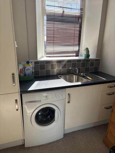 a kitchen with a washing machine and a sink at Splash Cottage beach house with Sea lapping Garden in Bangor