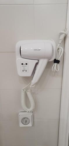 a white hairdryer hanging on a wall at Jasmine Home, Aegina City in Aegina Town