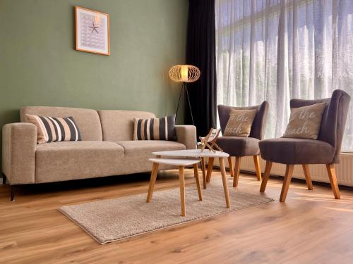 a living room with a couch and two chairs and a table at Reumann Holiday Apartments De Schelp 12 in Zandvoort