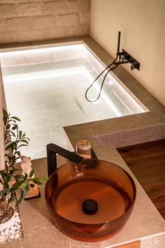 a sink with a wooden bowl on a counter next to a bath tub at Adalina Luxury Suite in Giovinazzo