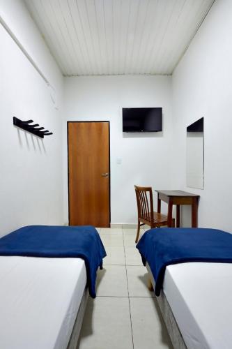 two beds in a room with a table and a chair at HOTEL & HOSTEL RIBEIRAo in Ribeirão Preto
