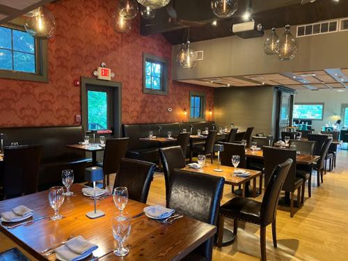 a restaurant with wooden tables and chairs with wine glasses at Butter milk falls inn in Milton