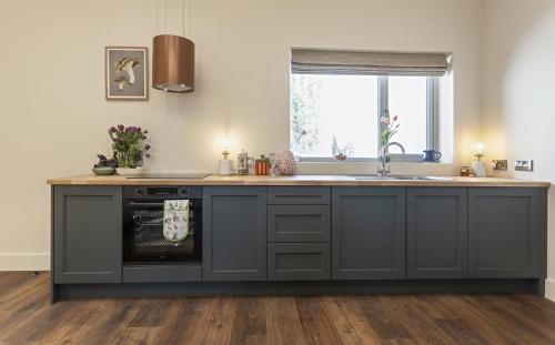 a kitchen with gray cabinets and a sink and a window at Castlestone Holiday Cottages & Townhouses in Naas