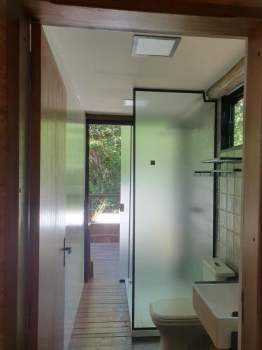 a bathroom with a toilet and a glass door at Chalé Bem-Te-Vi Cachoeira & SPA in Brotas
