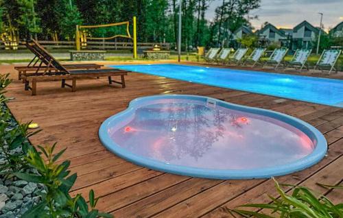 a hot tub sitting on a deck next to a swimming pool at Amazing Home In Niechorze With Sauna in Niechorze