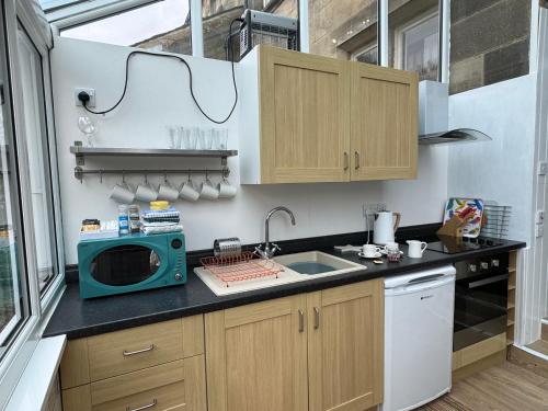 a small kitchen with a microwave and a sink at Hargate Hall Self Catering in Buxton