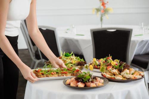 a woman is holding three plates of food on a table at Holiday Inn Sydney Potts Point in Sydney