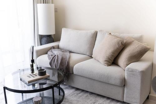 a living room with a couch and a glass table at Tranquil 1BR Hideaway in Damac Hills in Dubai Marina