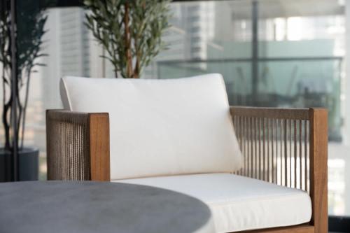 a wooden chair with a white cushion sitting next to a table at Tranquil 1BR Hideaway in Damac Hills in Dubai Marina