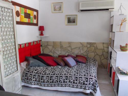 une chambre avec un lit avec des oreillers rouges et noirs dans l'établissement Studio confortable à Gaujac avec piscine partagée, à Gaujac