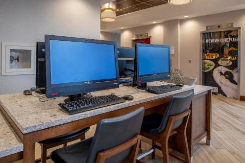 two computer monitors sitting on a desk with chairs at Crowne Plaza Hotel St. Louis Airport by IHG in Bridgeton
