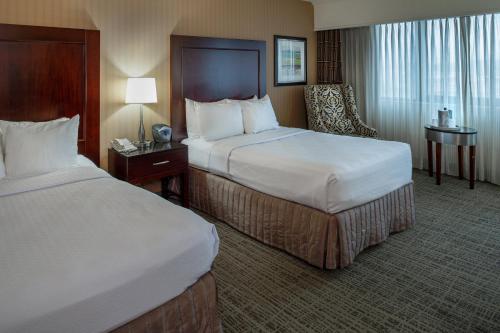 a hotel room with two beds and a chair at Crowne Plaza Hotel St. Louis Airport by IHG in Bridgeton