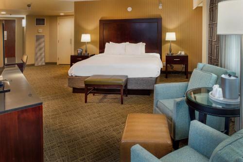 a large hotel room with a bed and chairs at Crowne Plaza Hotel St. Louis Airport by IHG in Bridgeton