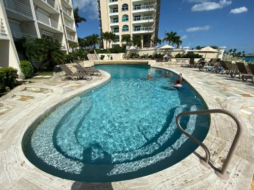 a swimming pool at a resort with people in it at Ocean Bliss: Balcony & Pools & Peloton Bike! in Lowlands
