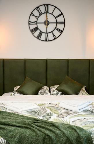 a clock on the wall above a bed at Brent Collection - Apartments in City Center in Novi Sad