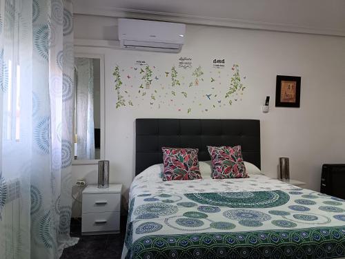 a bedroom with a bed with a black headboard and flowers on the wall at Casa Oasis Puertollano, una casa rural en Puertollano, agradable, con Piscina en zona tranquila in Puertollano