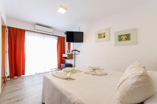 a white bed in a room with a tv at Hotel España in Mar del Plata