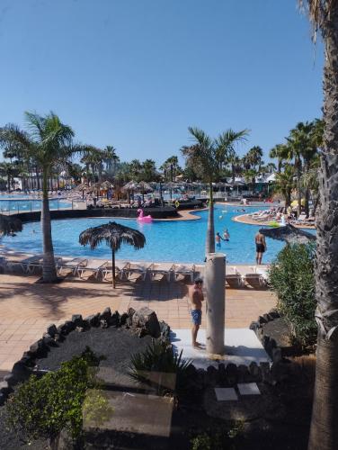 a child standing in front of a swimming pool at a resort at Oasis Duna - Casa Mariposa in Corralejo