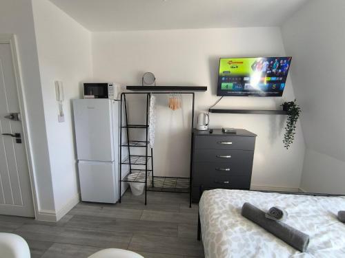 a room with a refrigerator and a tv on the wall at Tooting Broadway Family Suite in London